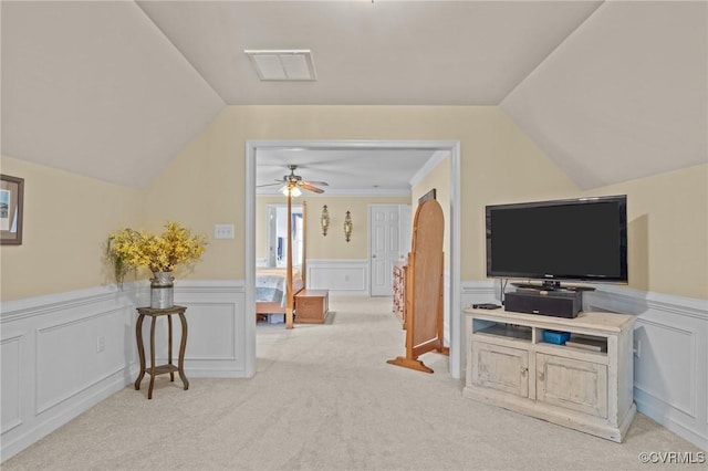 interior space featuring lofted ceiling, a wainscoted wall, visible vents, and a ceiling fan