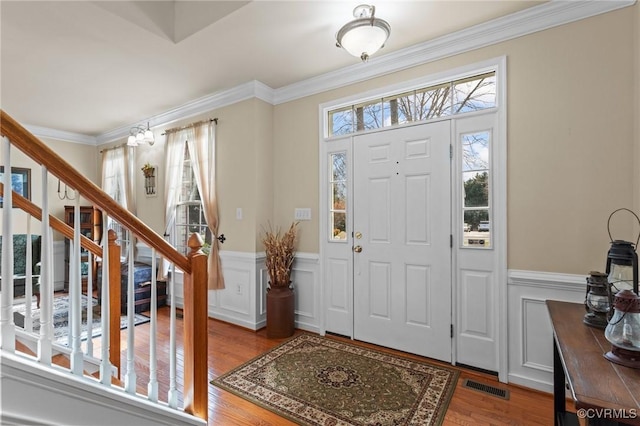 entryway featuring stairway, wood finished floors, visible vents, and crown molding