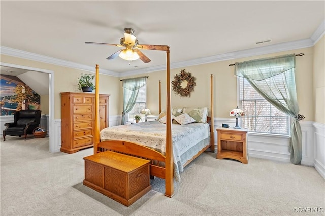 bedroom with multiple windows, wainscoting, visible vents, and light colored carpet