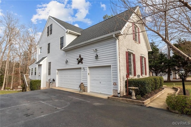 view of home's exterior with an attached garage, a shingled roof, and aphalt driveway