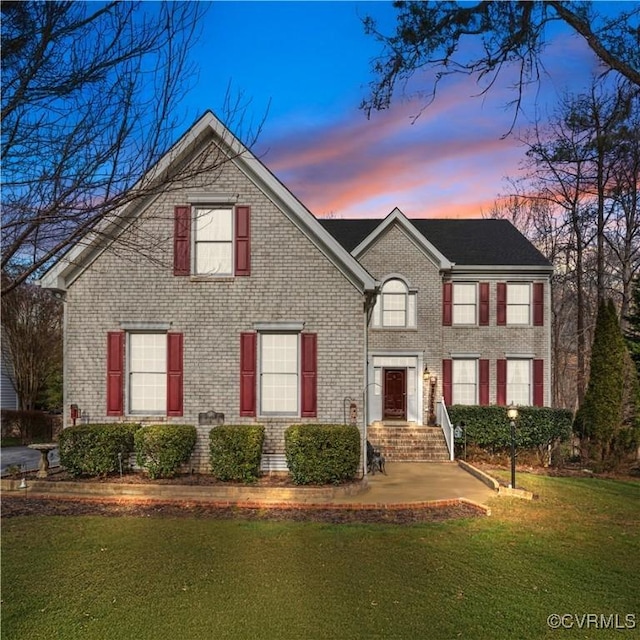 view of front of property featuring brick siding and a lawn