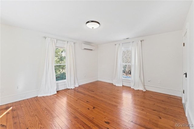 unfurnished room featuring an AC wall unit, baseboards, and wood finished floors