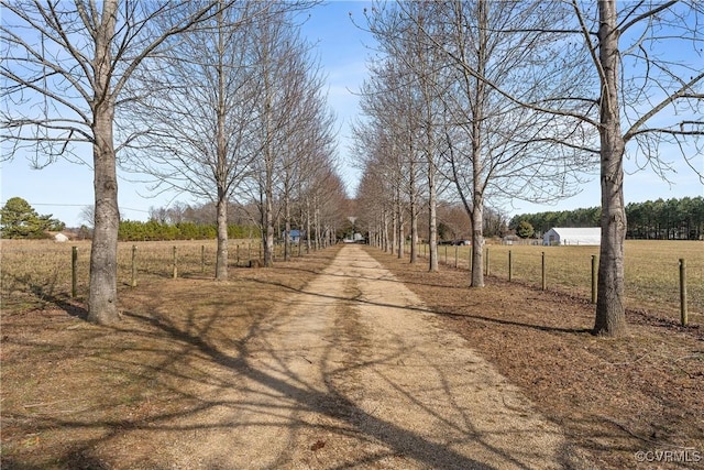 view of road featuring dirt driveway and a rural view