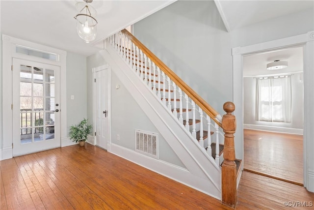 stairs with wood finished floors, visible vents, and baseboards