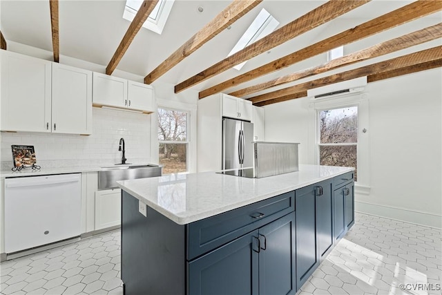 kitchen featuring freestanding refrigerator, white cabinets, a sink, blue cabinets, and dishwasher