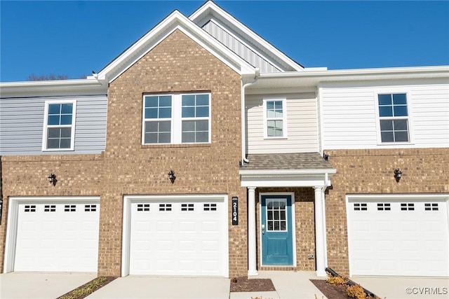 townhome / multi-family property with an attached garage, a shingled roof, concrete driveway, and brick siding