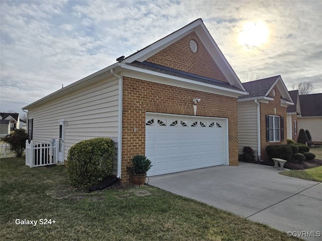 property exterior at dusk with an attached garage, a yard, driveway, and brick siding