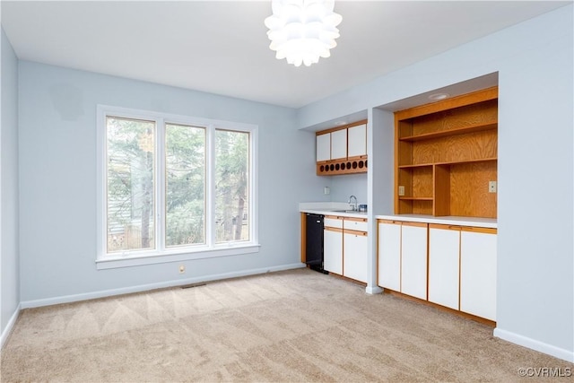 kitchen with open shelves, light countertops, light carpet, and white cabinetry