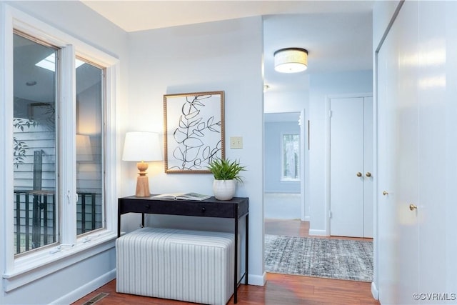 corridor featuring baseboards, visible vents, radiator heating unit, and wood finished floors