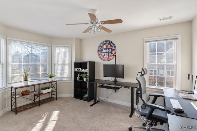 office featuring a ceiling fan, light colored carpet, visible vents, and baseboards