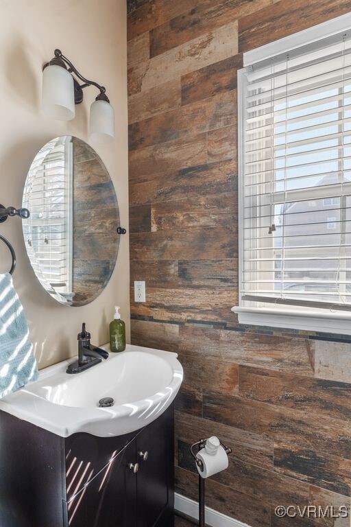 half bath featuring wooden walls and vanity