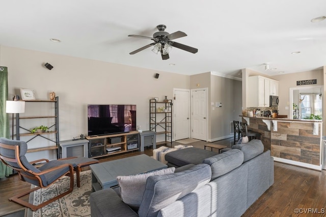 living area featuring dark wood-style flooring, a ceiling fan, and baseboards