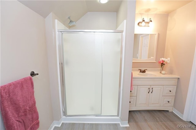 bathroom with wood finished floors, a shower stall, vanity, and baseboards