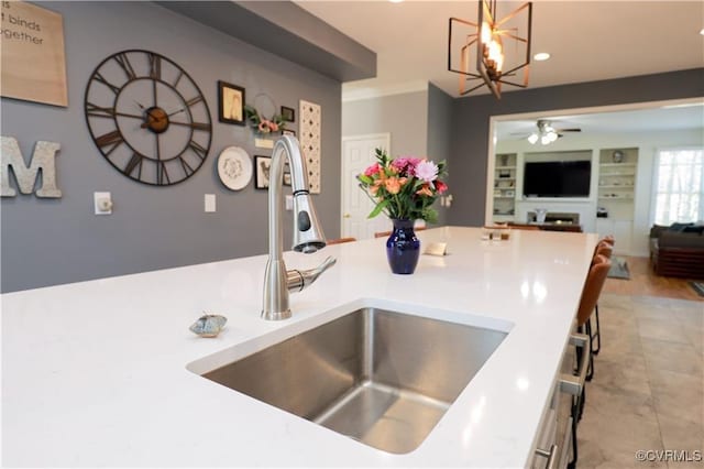 kitchen featuring built in shelves, pendant lighting, light countertops, open floor plan, and a sink