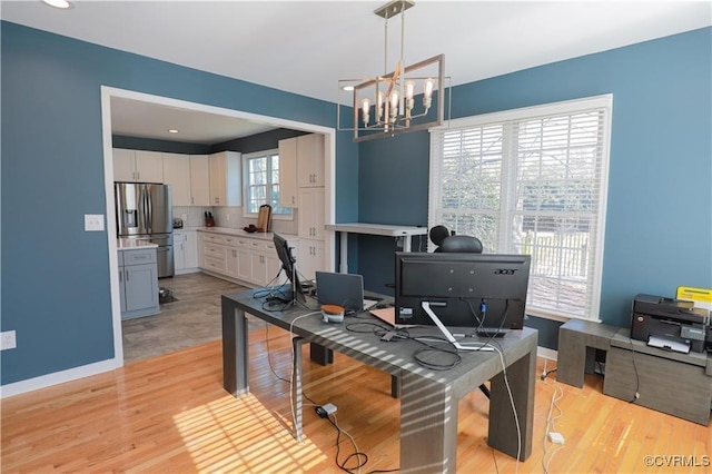 office space featuring baseboards, light wood finished floors, and an inviting chandelier