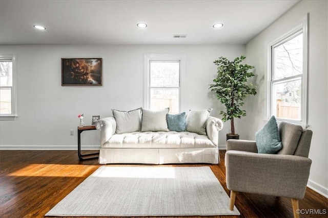 living room featuring dark wood finished floors, visible vents, and a healthy amount of sunlight