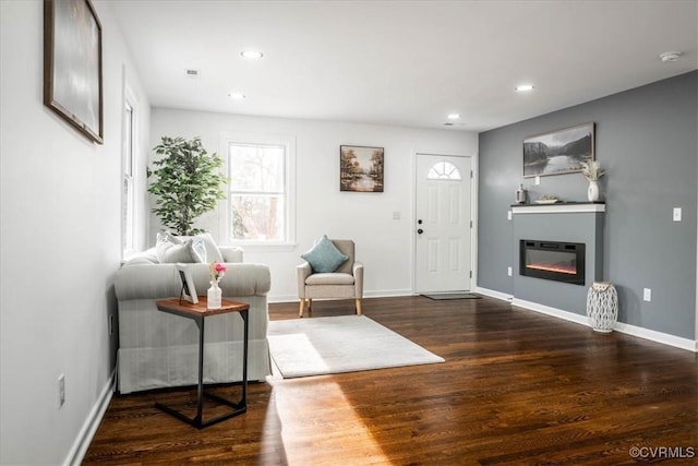 entrance foyer with a glass covered fireplace, dark wood finished floors, baseboards, and recessed lighting