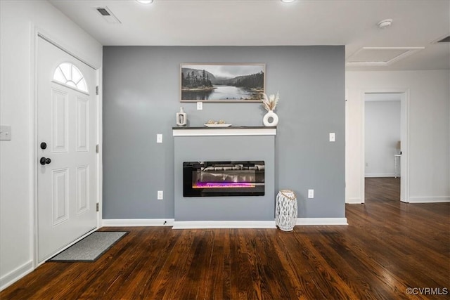 foyer featuring baseboards, dark wood-type flooring, and a glass covered fireplace