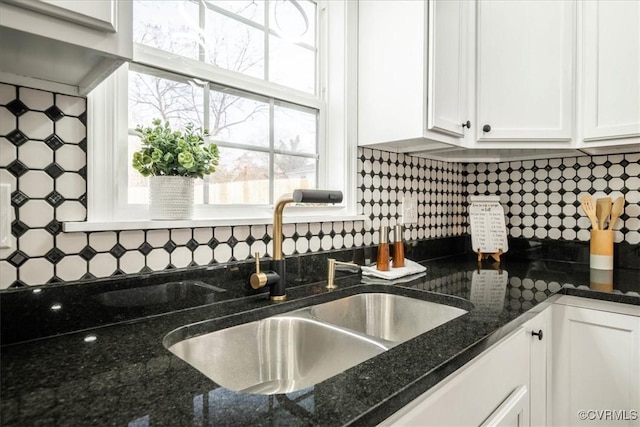 kitchen featuring dark stone counters, backsplash, a sink, and white cabinets