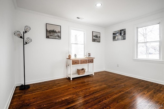 unfurnished room featuring dark wood-type flooring, visible vents, crown molding, and baseboards