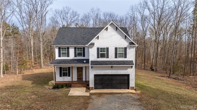 modern inspired farmhouse with a garage, driveway, roof with shingles, a front yard, and a wooded view