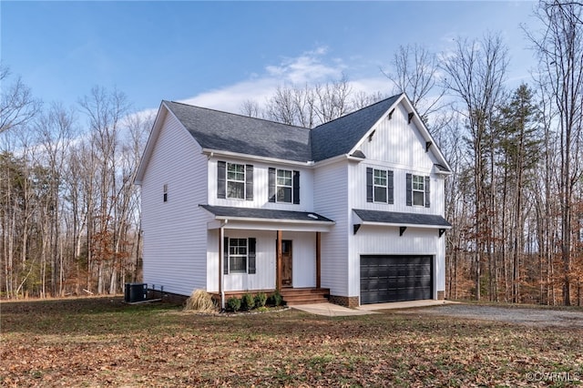 view of front of house with roof with shingles, covered porch, central AC unit, a garage, and driveway