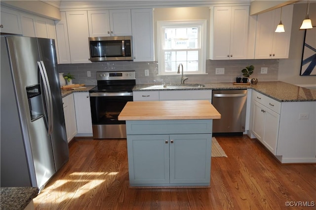 kitchen with a sink, white cabinetry, stainless steel appliances, and wooden counters