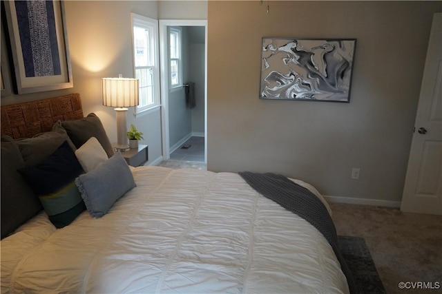 bedroom with light colored carpet, baseboards, and ensuite bathroom