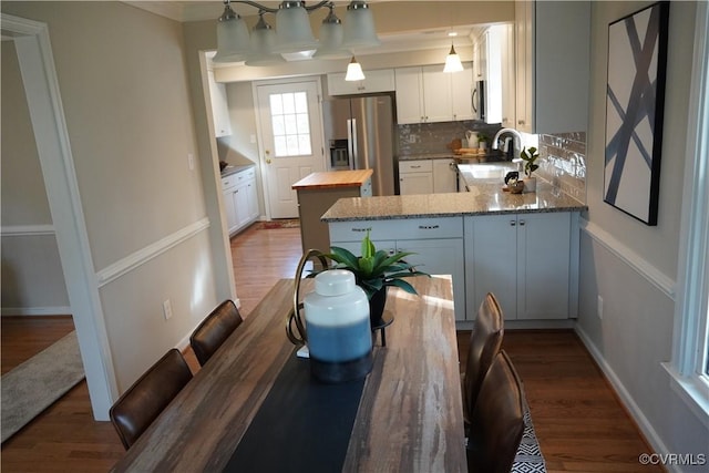 kitchen featuring butcher block counters, decorative light fixtures, stainless steel appliances, white cabinetry, and a sink