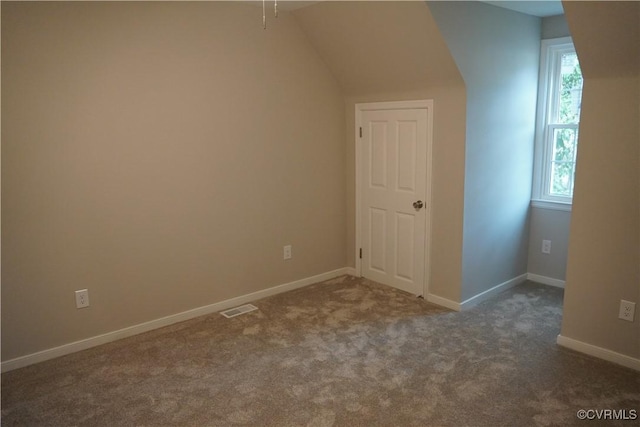 additional living space featuring baseboards, visible vents, and dark colored carpet