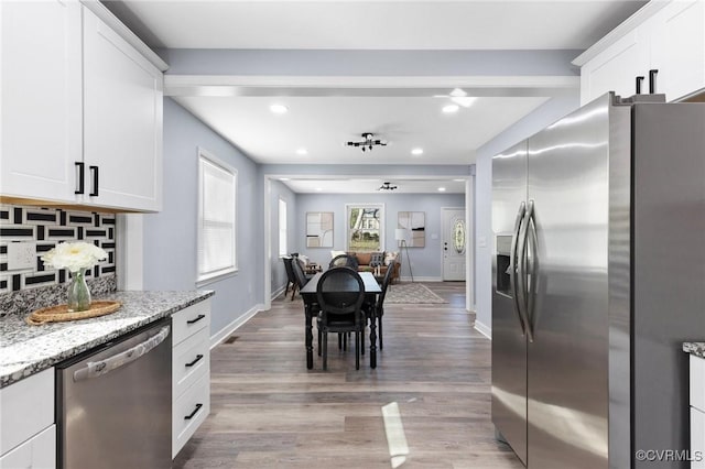 kitchen featuring stainless steel appliances, light stone counters, light wood-style flooring, and white cabinetry