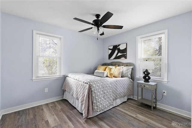 bedroom with multiple windows, baseboards, and dark wood finished floors