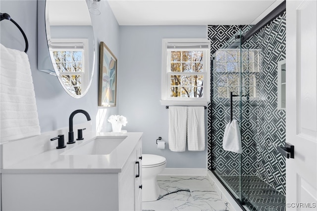 bathroom featuring marble finish floor, toilet, a stall shower, vanity, and baseboards