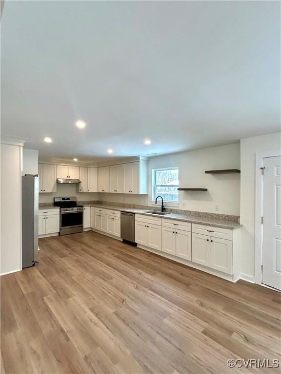 kitchen with white cabinets, appliances with stainless steel finishes, light wood-type flooring, under cabinet range hood, and a sink