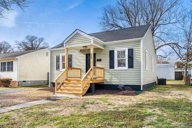 bungalow-style home featuring a shingled roof, a front yard, and crawl space