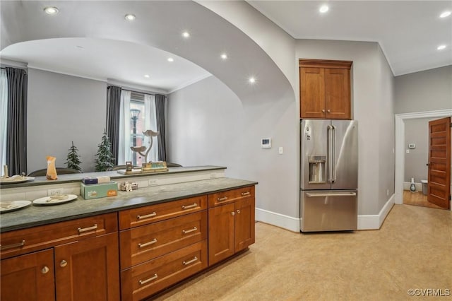 kitchen with arched walkways, recessed lighting, light carpet, high end refrigerator, and baseboards