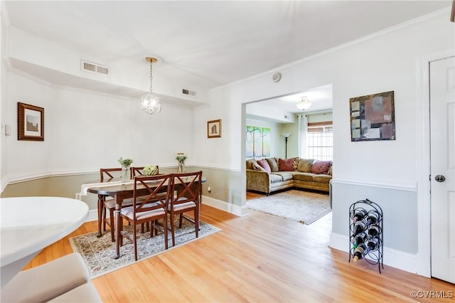 dining room featuring visible vents, wood finished floors, and ornamental molding