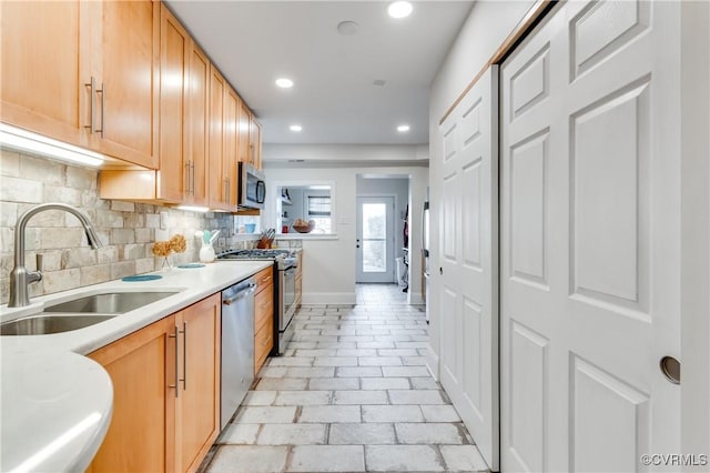 kitchen featuring recessed lighting, stainless steel appliances, a sink, light countertops, and backsplash