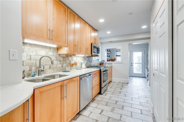 kitchen featuring stainless steel appliances, recessed lighting, tasteful backsplash, light countertops, and a sink