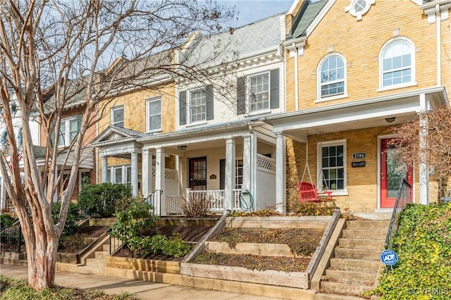 view of property with covered porch and brick siding