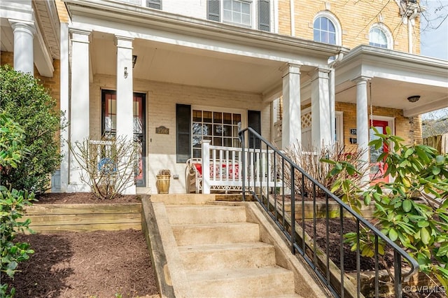 entrance to property with covered porch and brick siding