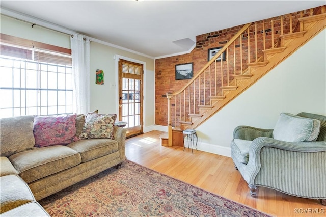 living area with stairs, ornamental molding, wood finished floors, and baseboards