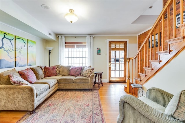 living area featuring ornamental molding, stairway, wood finished floors, and visible vents