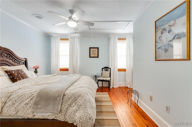 bedroom with light wood finished floors, attic access, multiple windows, and ornamental molding