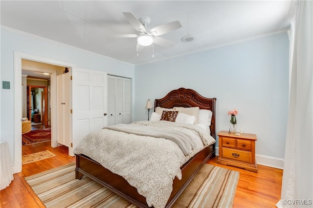 bedroom featuring baseboards, a ceiling fan, ornamental molding, light wood-style floors, and a closet