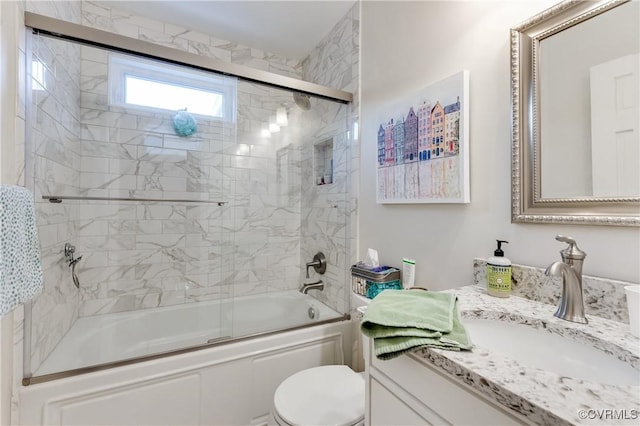 bathroom featuring toilet, shower / bath combination with glass door, and vanity