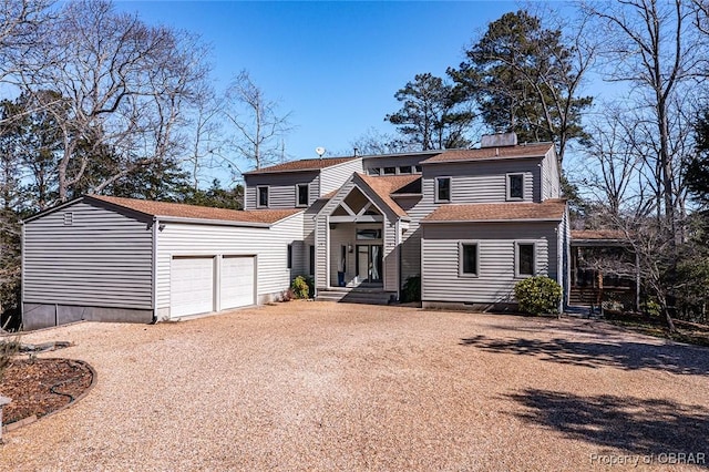 view of front facade with an attached garage, a chimney, and gravel driveway