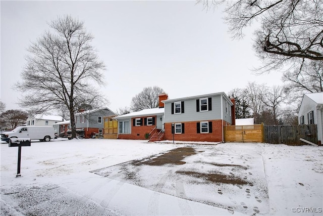 split level home with brick siding, fence, and a chimney