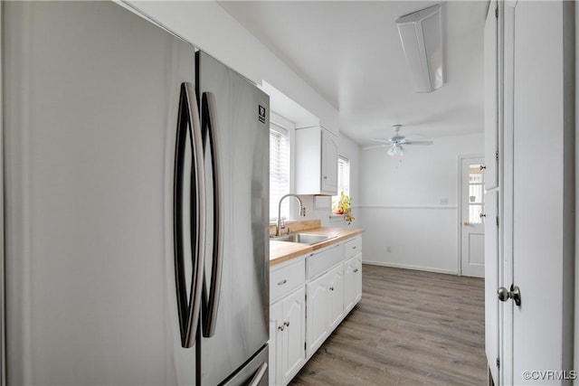 kitchen with light wood-style flooring, a sink, white cabinetry, light countertops, and freestanding refrigerator