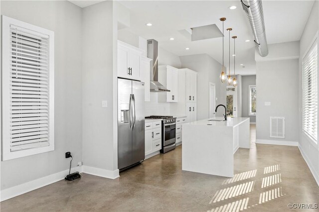 kitchen featuring white cabinets, light countertops, appliances with stainless steel finishes, wall chimney exhaust hood, and a center island with sink